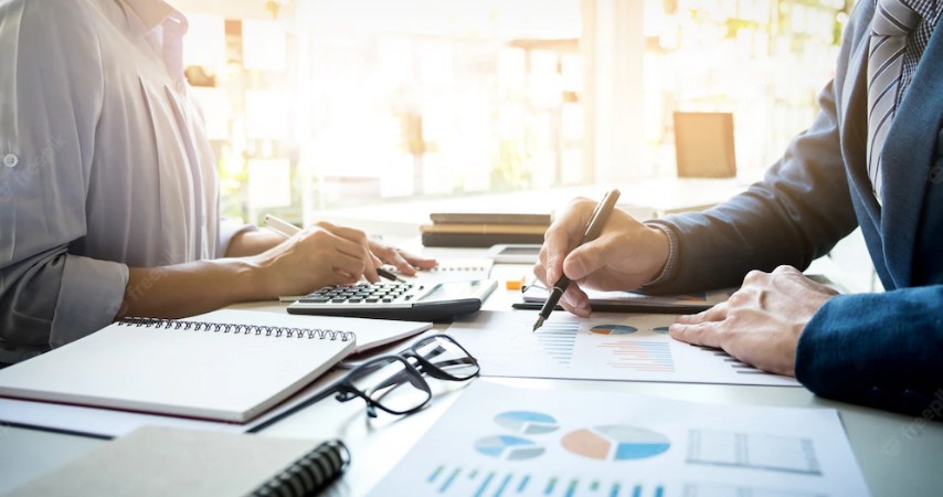 Dois homens analisando vários gráficos em uma mesa de escritório.