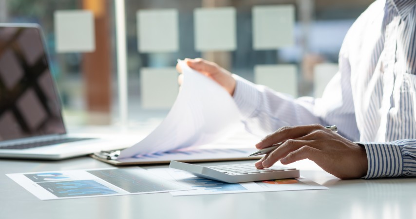 Homem analisando documentos e calculando em uma calculadora
