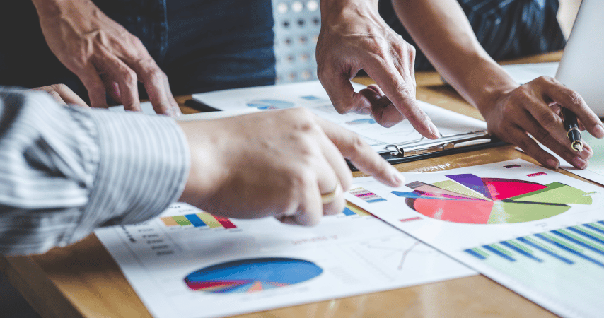 Mãos analisando um papel com gráficos, mostrando que uma auditoria financeira para empresas é essencial.