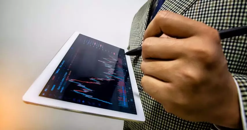 Homem analisando gráficos estilo eletro cardiograma, na tela de um tablet. 